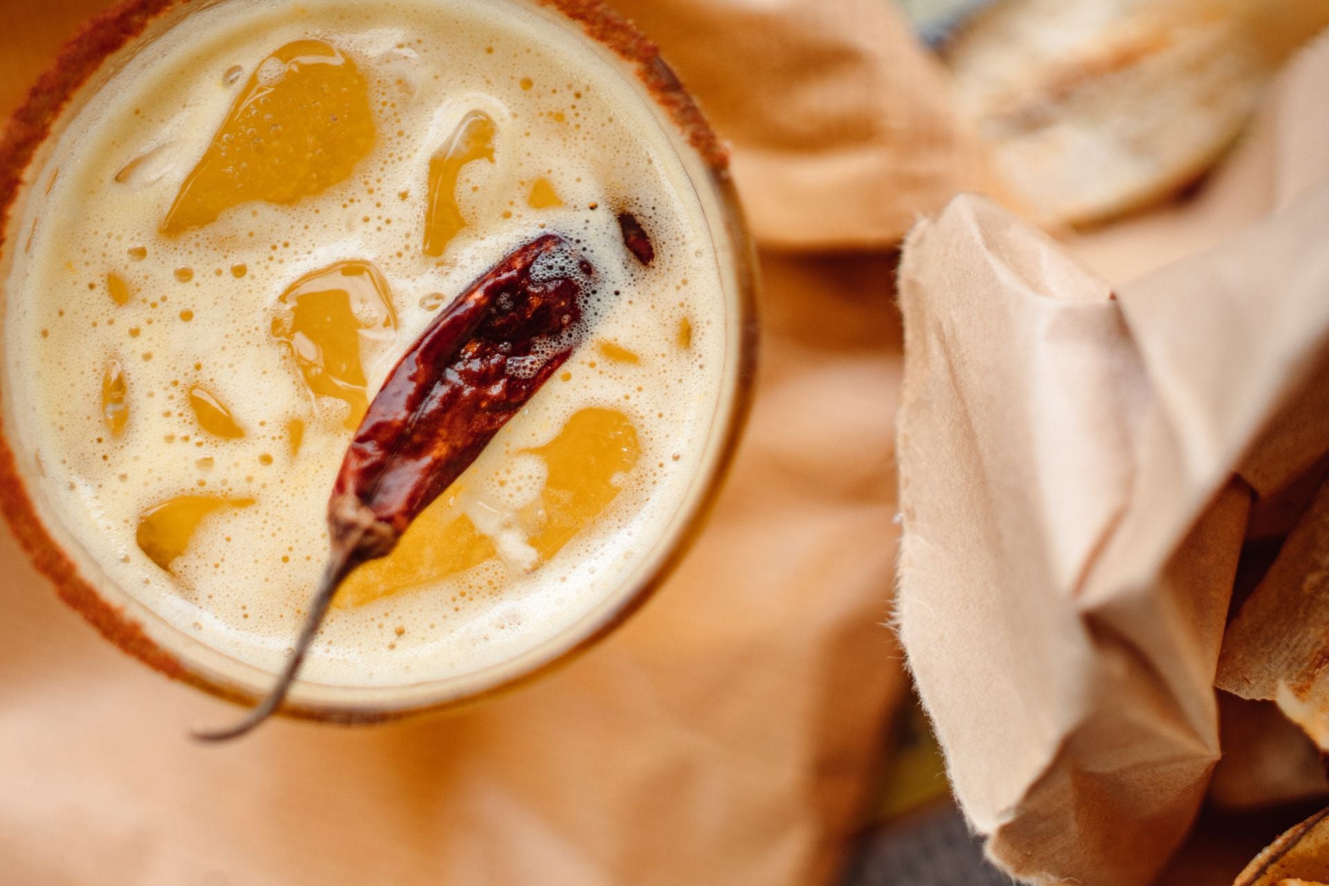 top view of glass of orange spicy cocktail with chilli pepper in it
